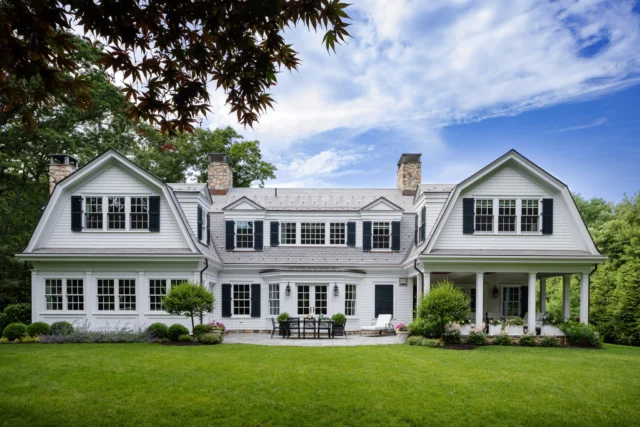 Classic New England charm with timeless appeal in Falmouth. Twin gambrel roofs, stone chimneys, and shuttered windows define this Shingle Style retreat, while a gracious covered porch and landscaped patio invite effortless coastal living. A home designed to feel both historic and enduringly welcoming.

Architecture: @patrickahearnarchitect 
Photo Credit: @gregpremru