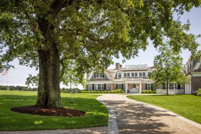 Beneath a broad-canopied tree in Duxbury, MA, a simple swing offers a quiet welcome in the motor court, where a stately bayfront gambrel with classic shingled lines sits beyond a gently curving drive.

Architecture: @patrickahearnarchitect 
Builder: @jbrobbiecustomhomes 
Landscape: @leblancjones 
Photo Credits: @taylor.allegrini